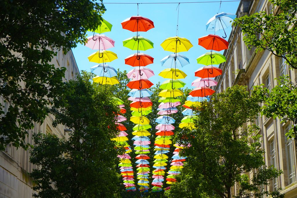 A colorful array of umbrellas hangs between buildings in a lively street in Liverpool, UK.