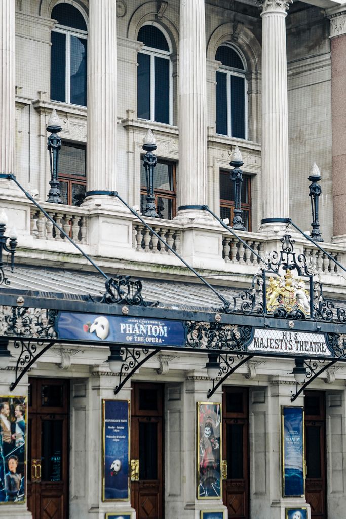 Exterior view of Her Majesty's Theatre in London, showcasing classic architecture with Phantom of the Opera signage.
