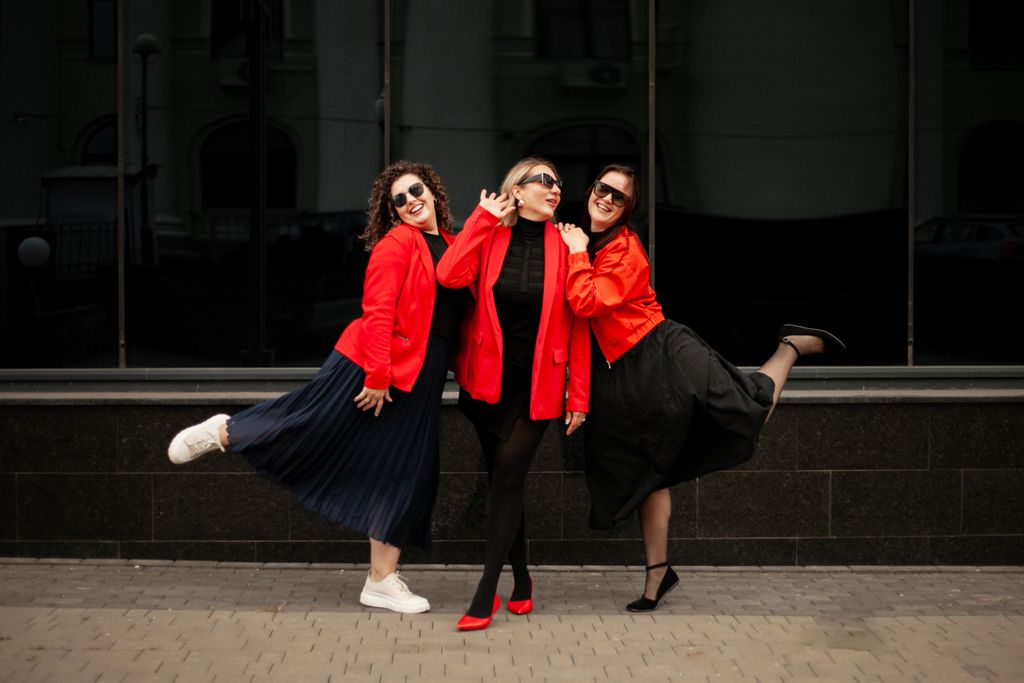 Three women exuding joy and style in vibrant red jackets, striking a pose outdoors.